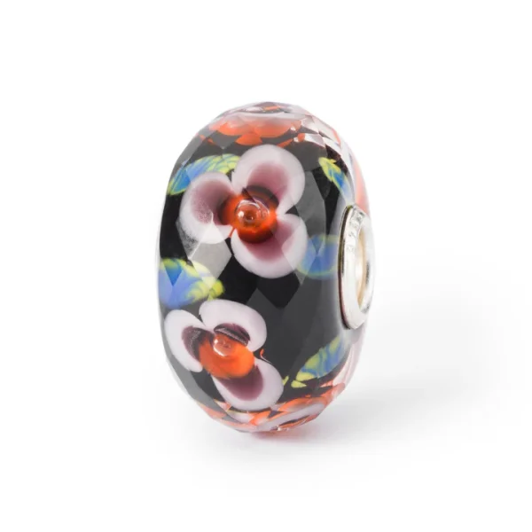 Bead Trollbeads Fiori di Campo in vetro sfaccettato con decorazioni floreali su base scura e anima in argento 925.