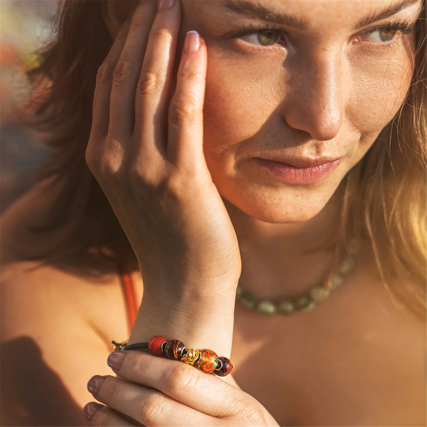 Bead in vetro Anima dei fiori Trollbeads TGLBE-30196 con decorazioni floreali interne arancioni e verdi e inserto centrale in argento 925.