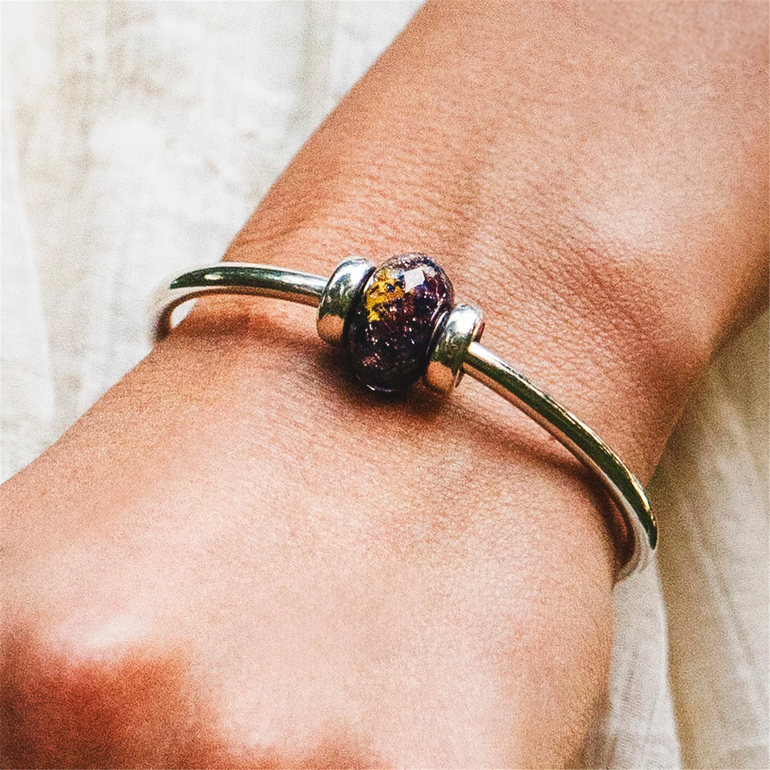 Bead Serata Estiva Trollbeads TGLBE-30223 People's Bead 2026 in vetro sfaccettato blu con dettagli dorati.
